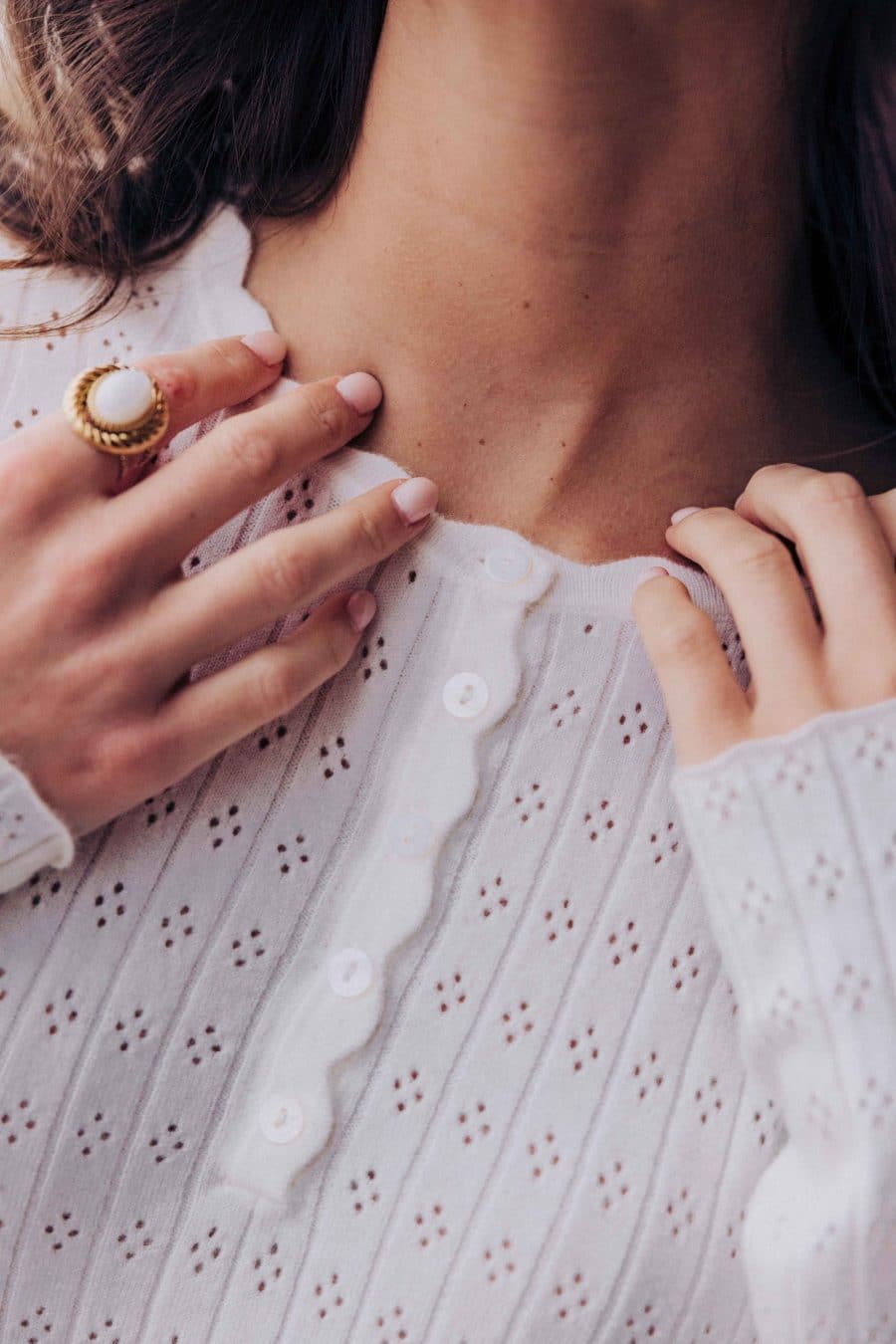 Top Elowan Sahoma blanc en maille ajourée et col tunisien, manches longues, portée avec un jean bleu foncé