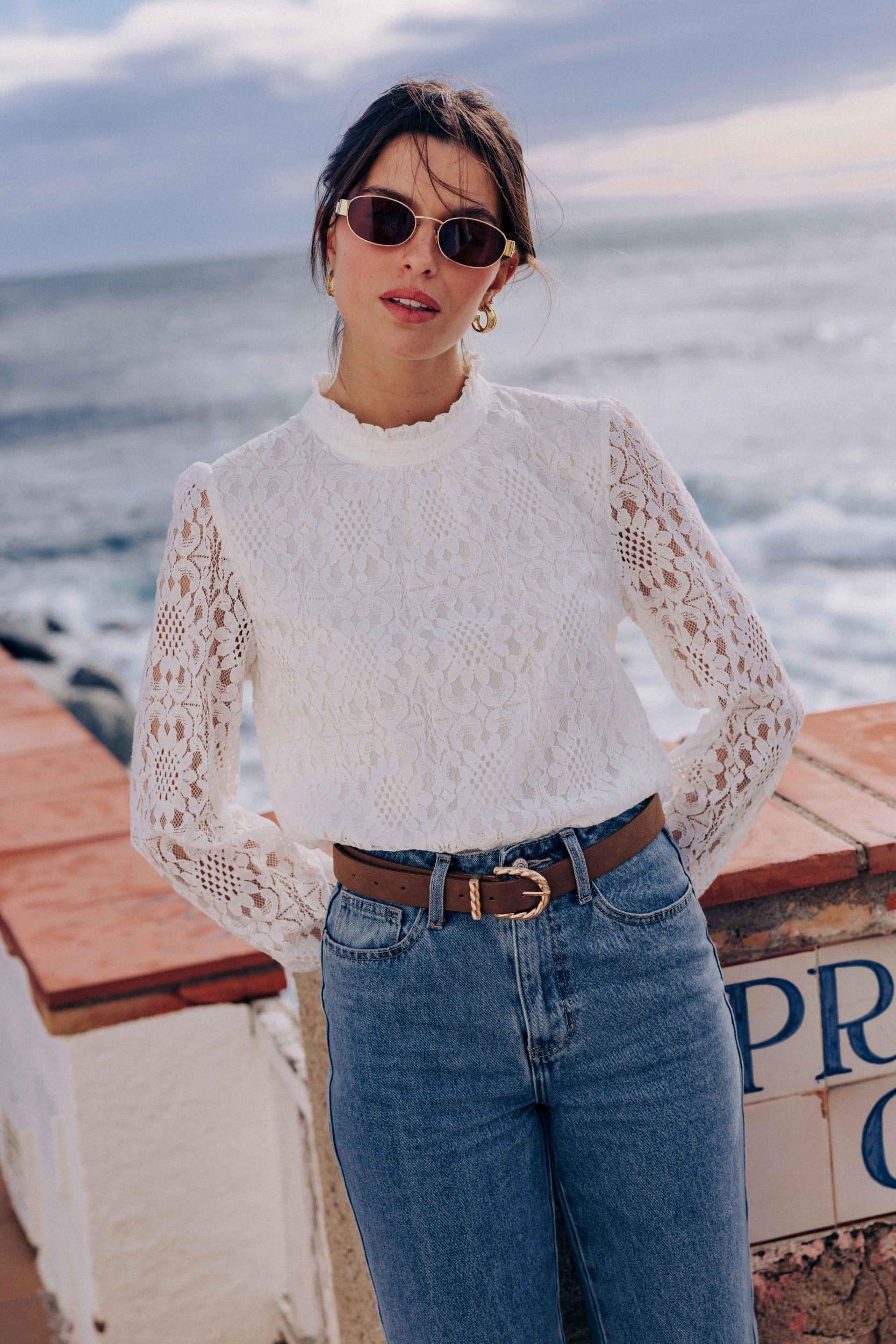 blouse-leona-blanche-sahoma-00004 Blouse Leona Sahoma blanche aux motifs floraux en dentelle, col montant à volants, manches longues, portée avec un jean bleu foncé