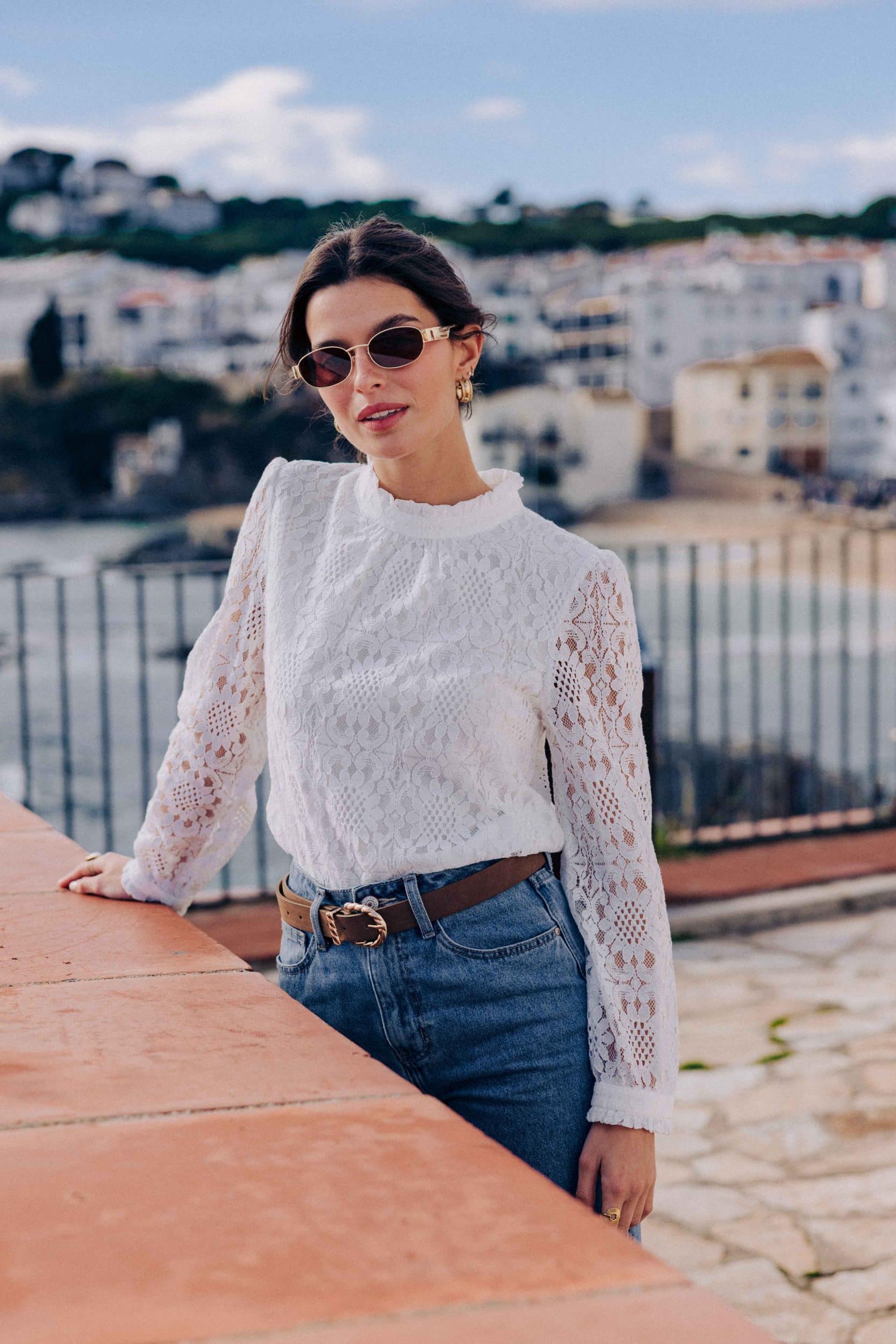 blouse-leona-blanche-sahoma-00005 Blouse Leona Sahoma blanche aux motifs floraux en dentelle, col montant à volants, manches longues, portée avec un jean bleu foncé