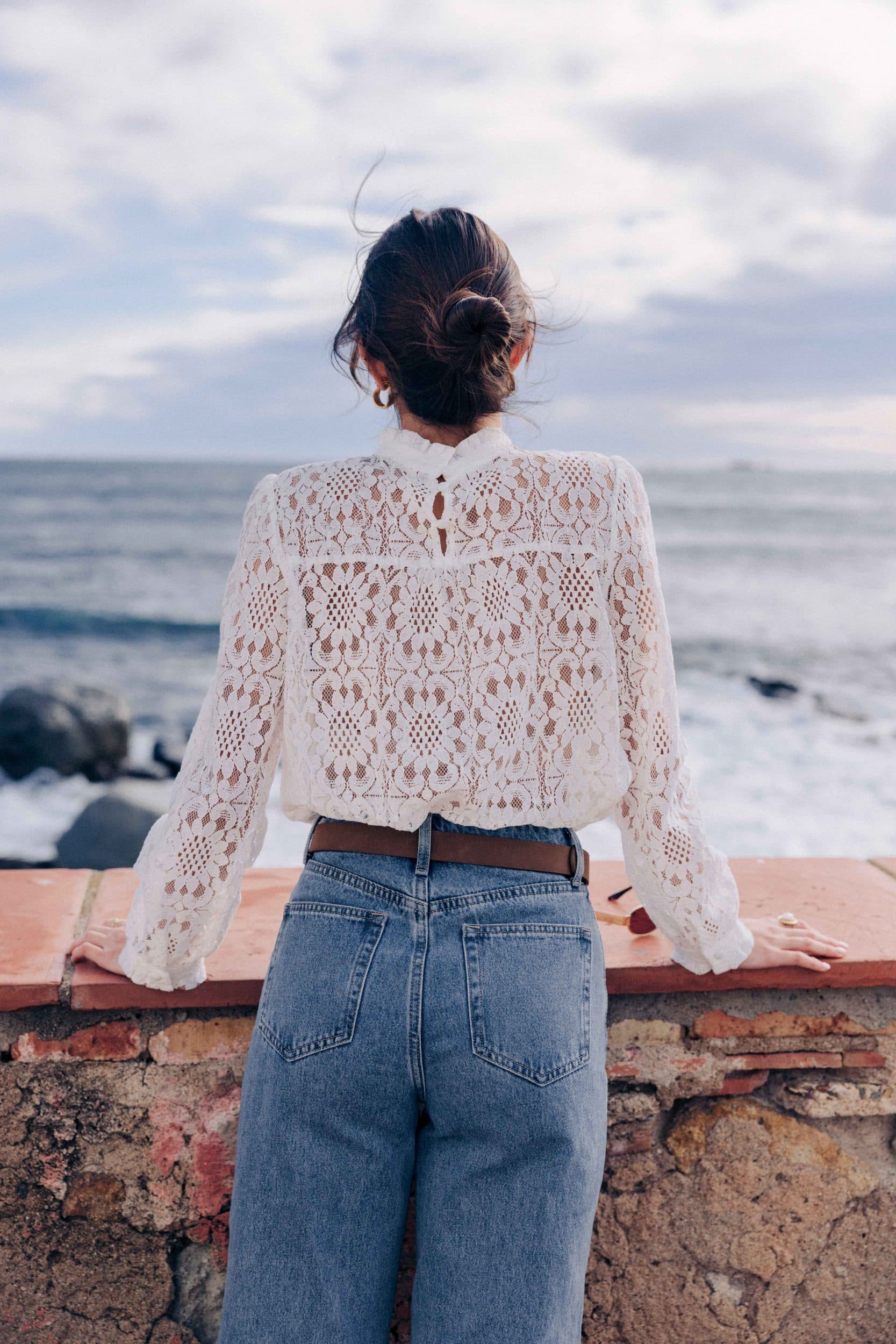 blouse-leona-blanche-sahoma-00006 Blouse Leona Sahoma blanche aux motifs floraux en dentelle, col montant à volants, manches longues, portée avec un jean bleu foncé