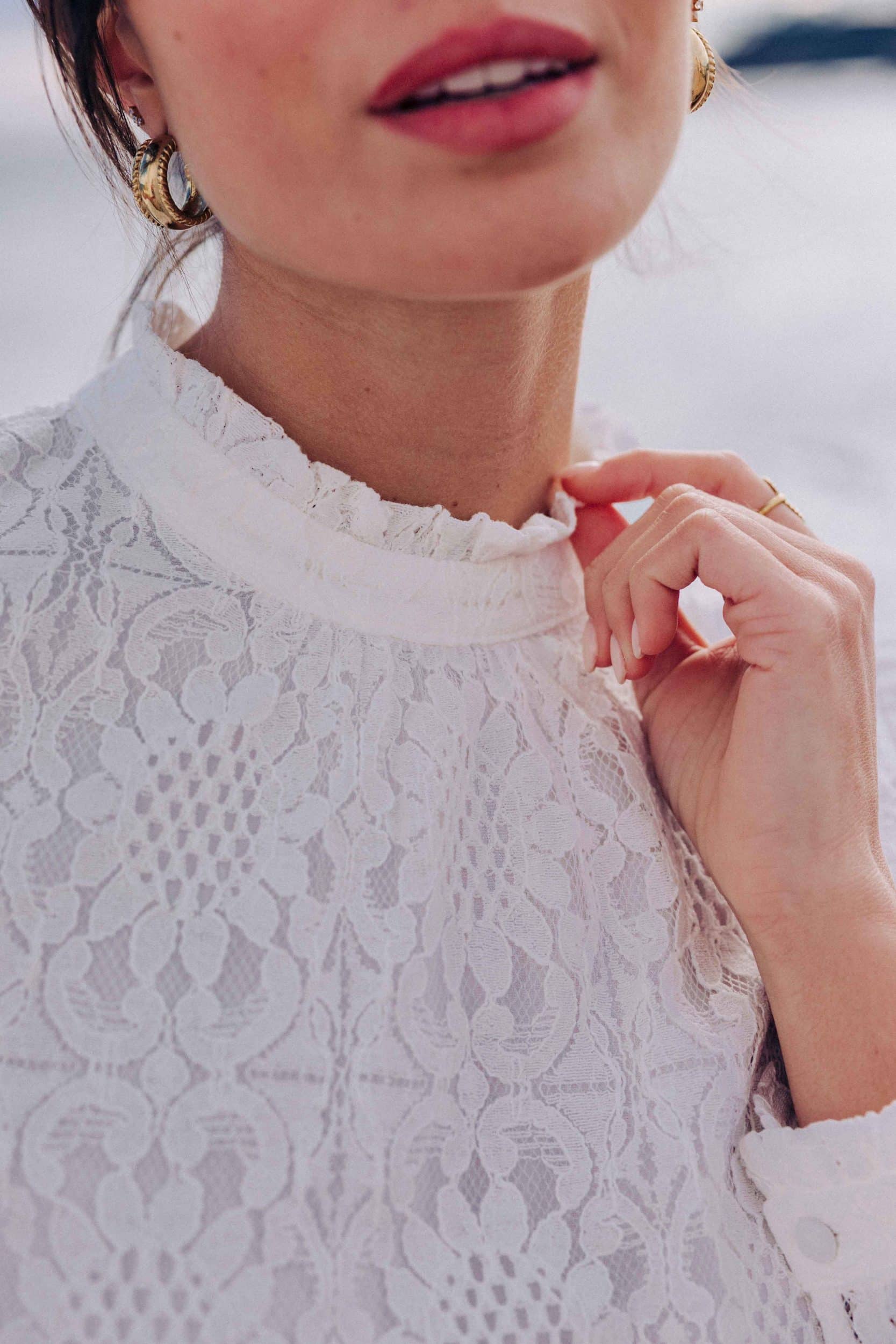 blouse-leona-blanche-sahoma-00007 Blouse Leona Sahoma blanche aux motifs floraux en dentelle, col montant à volants, manches longues, portée avec un jean bleu foncé