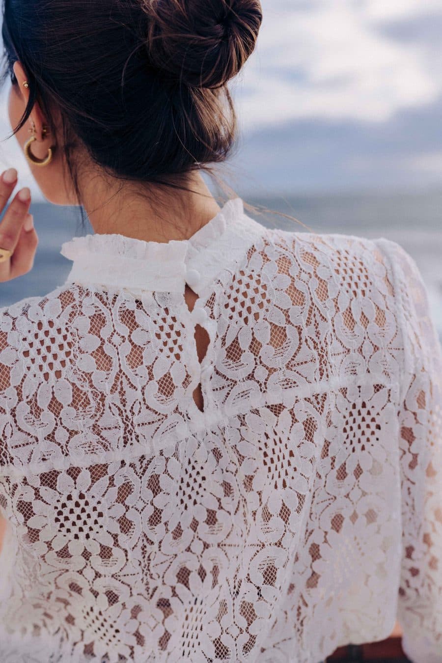 Blouse Leona Sahoma blanche aux motifs floraux en dentelle, col montant à volants, manches longues, portée avec un jean bleu foncé
