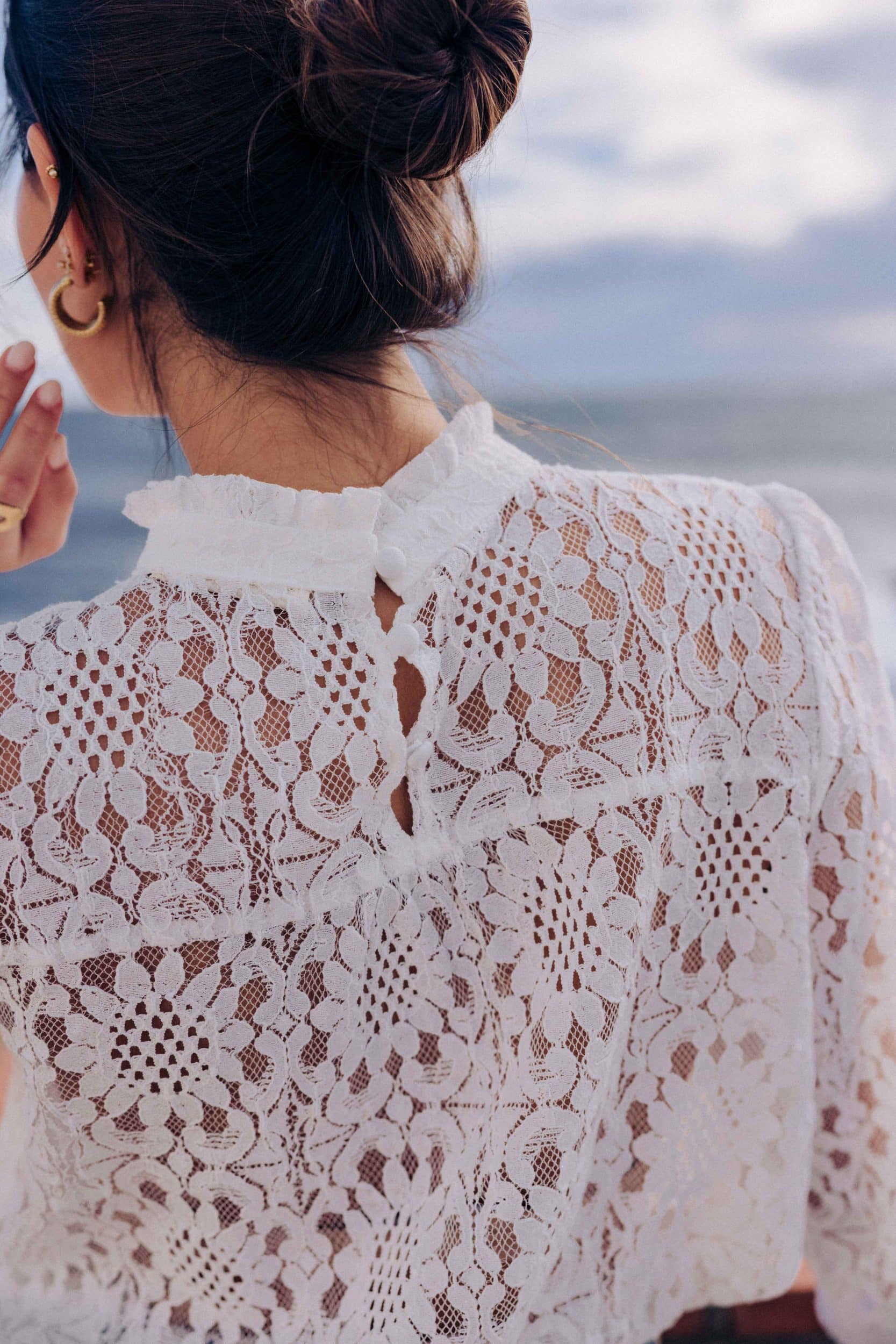 blouse-leona-blanche-sahoma-2 Blouse Leona Sahoma blanche aux motifs floraux en dentelle, col montant à volants, manches longues, portée avec un jean bleu foncé