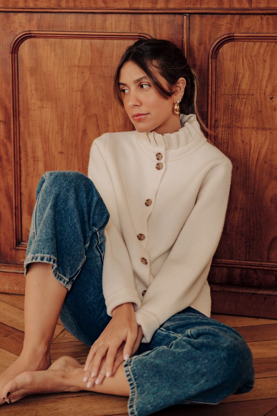 Gilet Flavie Sahoma écru uni à col montant à volants, manches longues, portée avec un jean bleu foncé