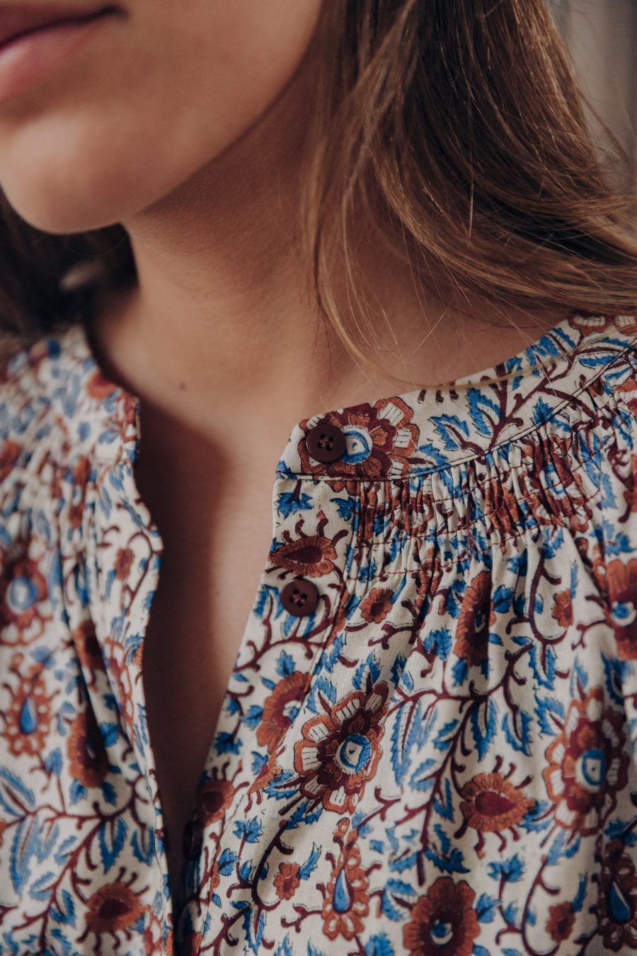 Détail de la blouse Bleona Sahoma imprimé fleuri, tons bleus beiges et marrons, boutonnée tout le long, col rond, manches longues