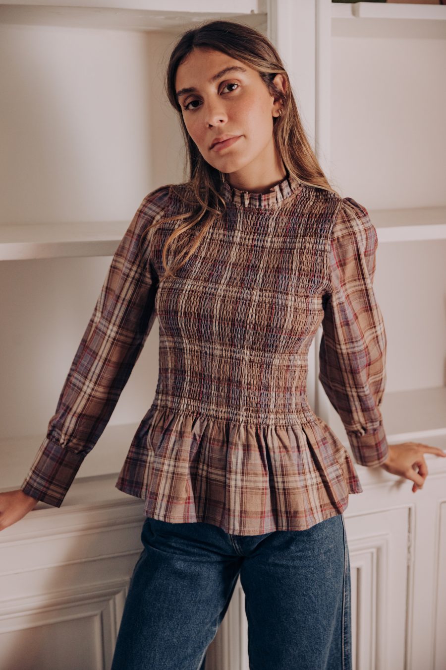 Blouse Briona marron à smocks, motif carreaux, finition bocage à manches longues portée avec le jean Omar bleu foncé