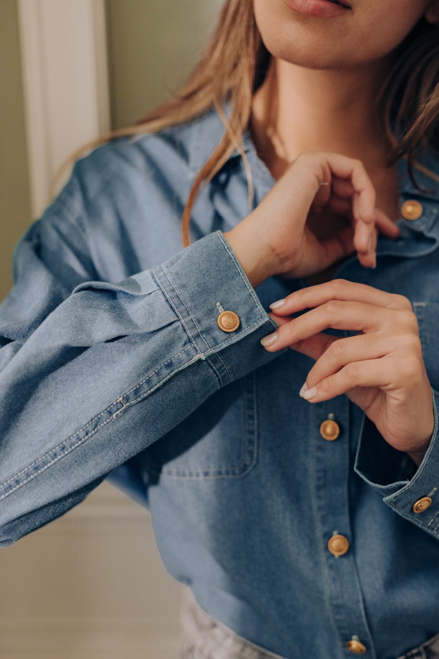 Détail poignet de la chemise femme Indira en jean bleu clair, poches plaquées sur la poitrine et boutons dorés blason, Sahoma