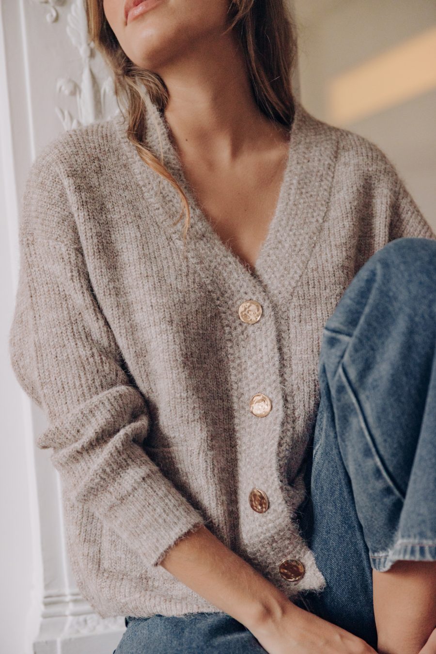 Gilet Sahoma Kolya taupe col V à boutons dorés martelés et manches longues porté avec le jean Omar bleu foncé