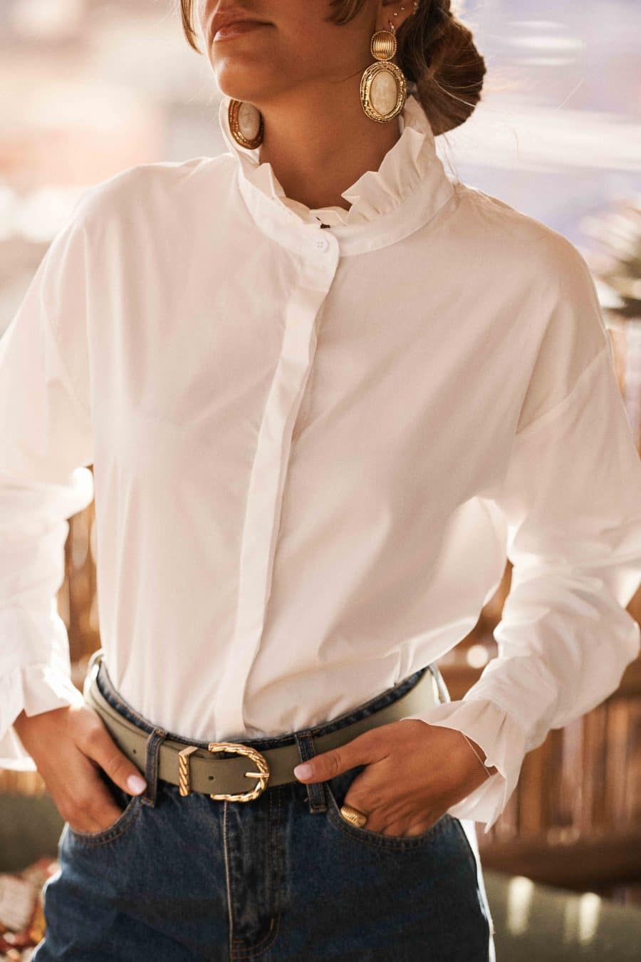 Chemise West Sahoma blanche, col montant à volants, manches longues, portée avec un jean bleu foncé