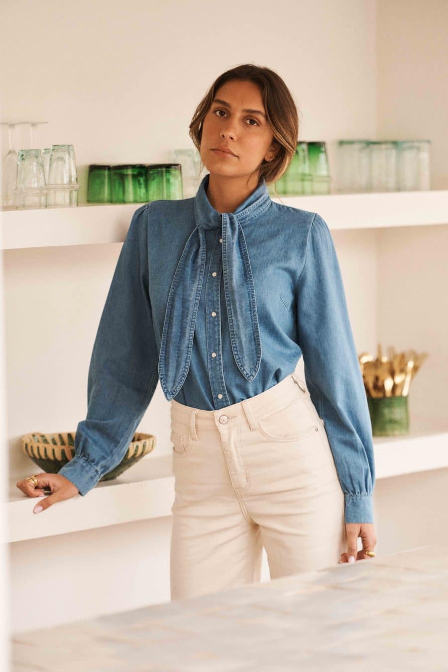 Chemise Evara Sahoma en jean bleu, manches longues et col lavallière, portée avec un jean blanc