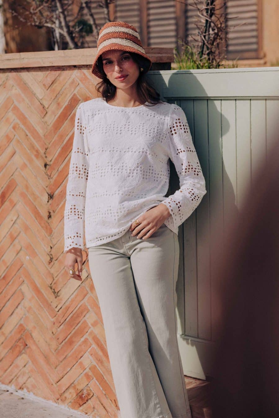 Blouse Zahara Sahoma blanche aux motifs floraux en broderie anglaise, col rond, manches longues, portée avec un jean