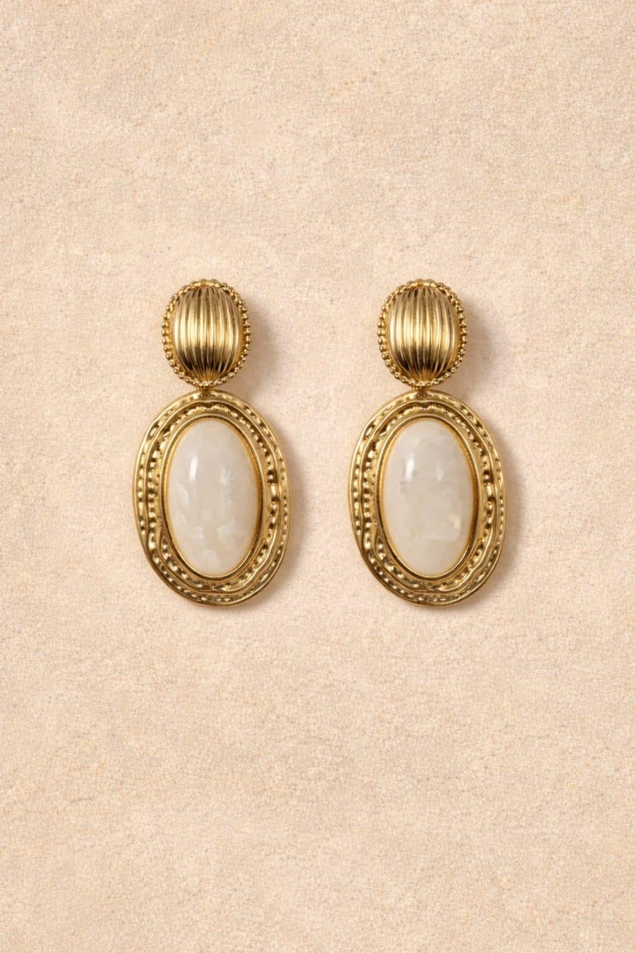 Boucles d'oreilles Eline Sahoma dorées ornées d'une pierre blanche en résine marbré, sur fond blanc