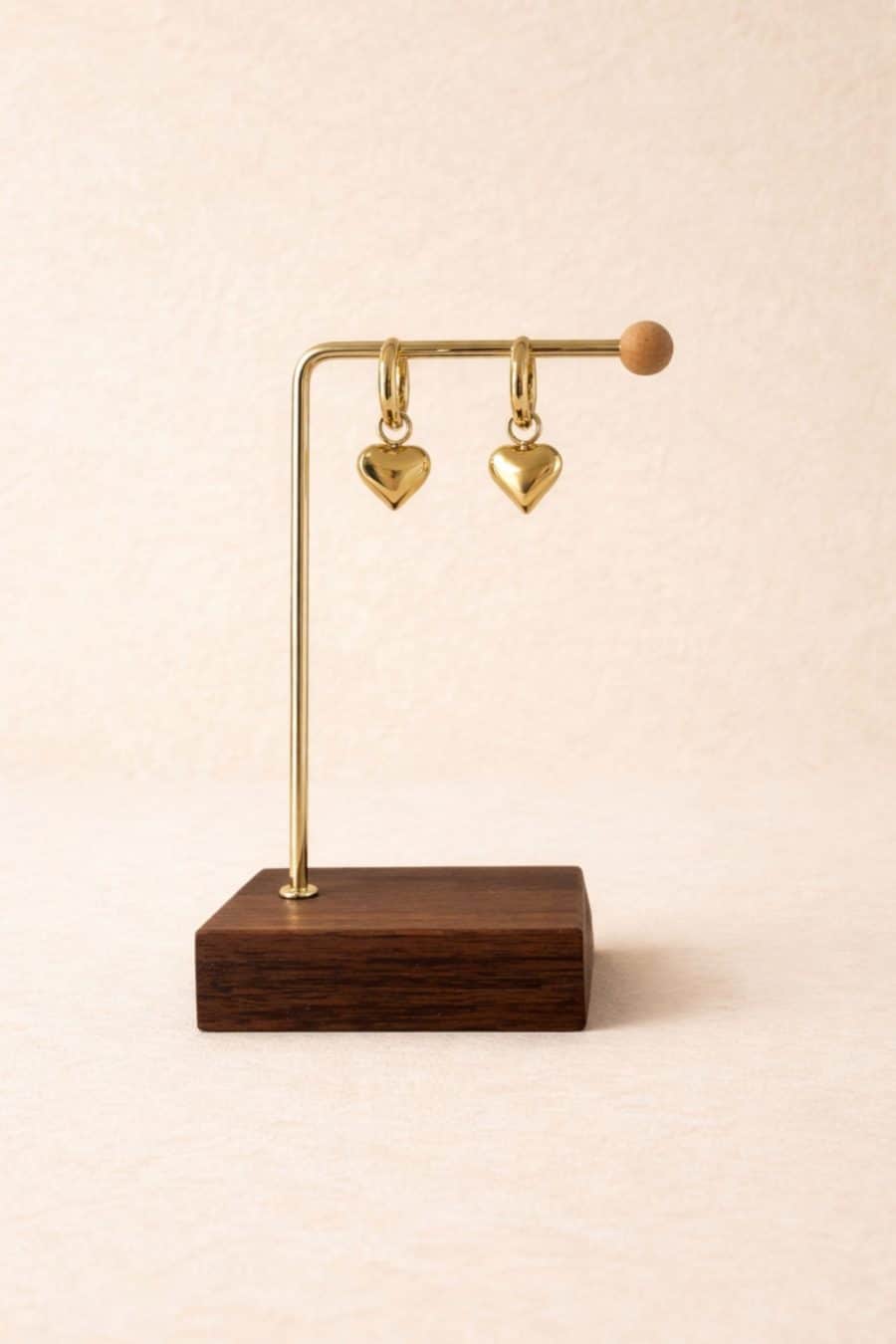 Boucles d'oreilles Romane Sahoma dorées ornée d'un pendentif forme coeur, portée en accumulation