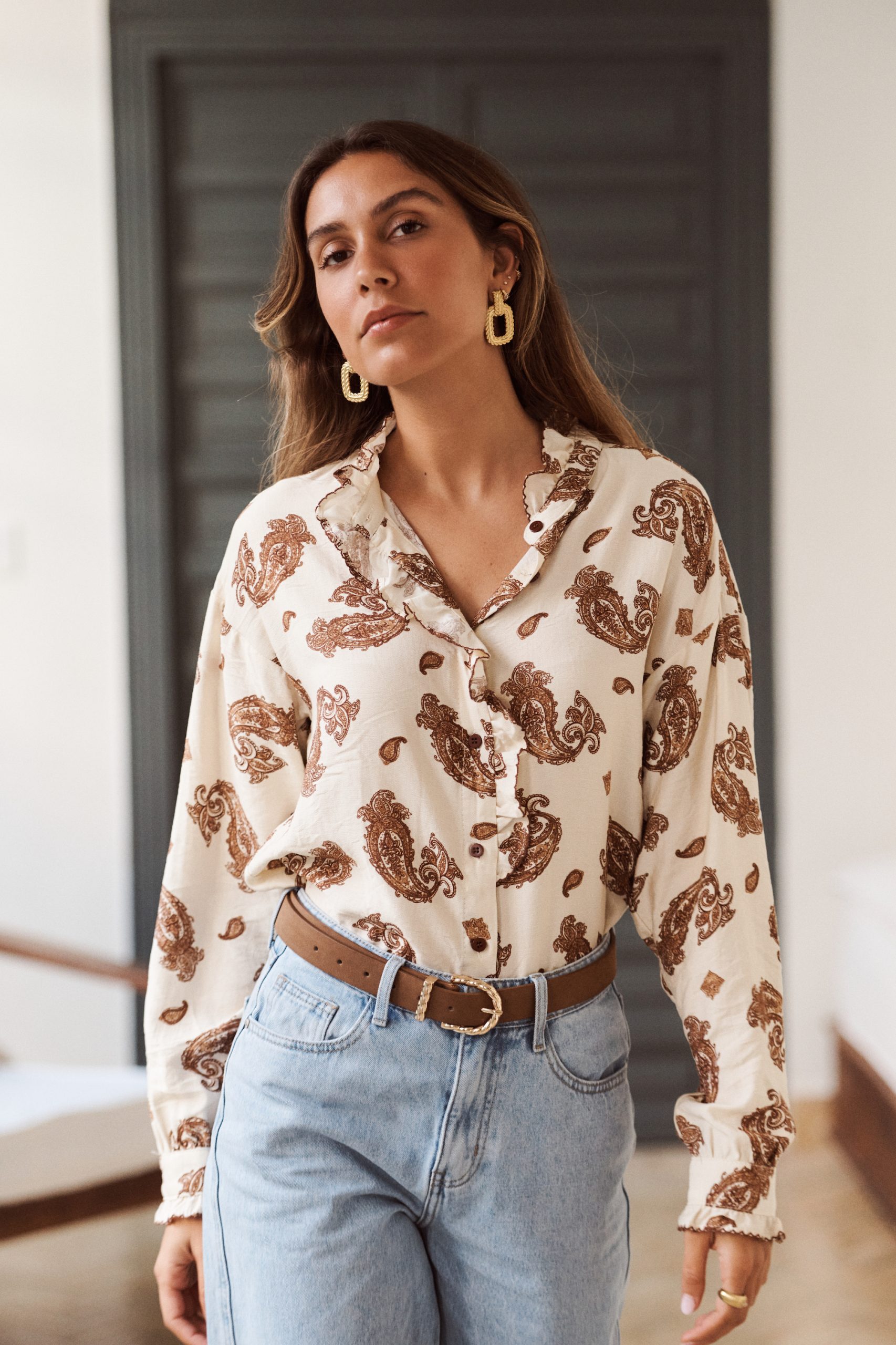 Chemise Inaé Sahoma en camaïeu marron, imprimé cachemire, col et jabot à volants, manches longues, portée avec un jean clair