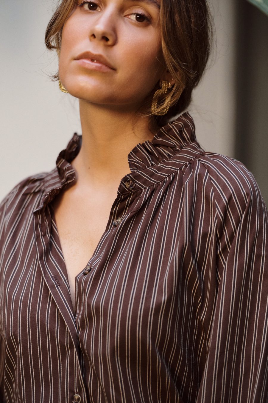 Chemise Zarela Sahoma rayée marron col montant à volants, manches longues, portée avec un pantalon beige en lin