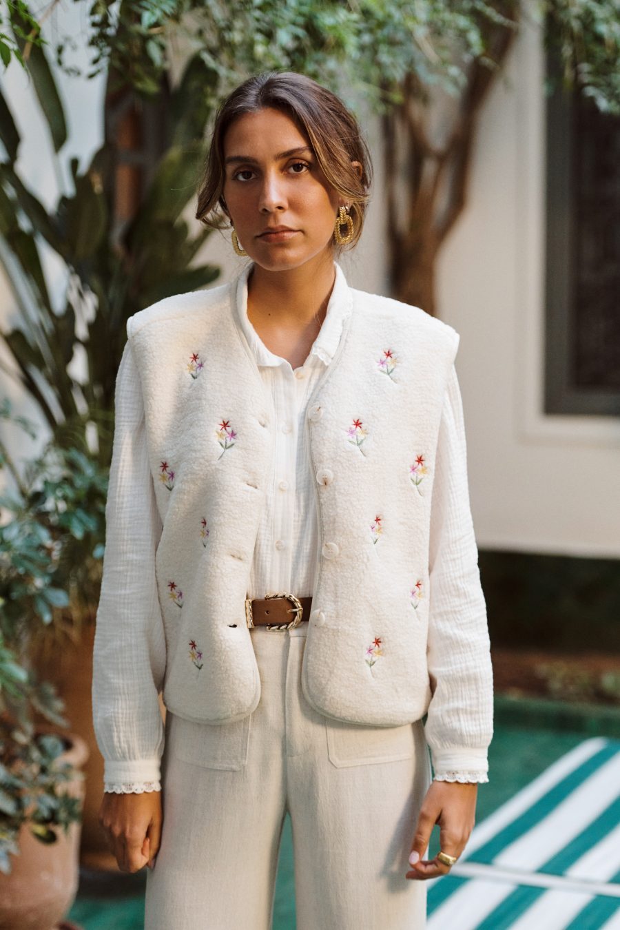 Gilet Celestine Sahoma en sherpa écru, sans manches à boutons porté avec un pantalon en lin