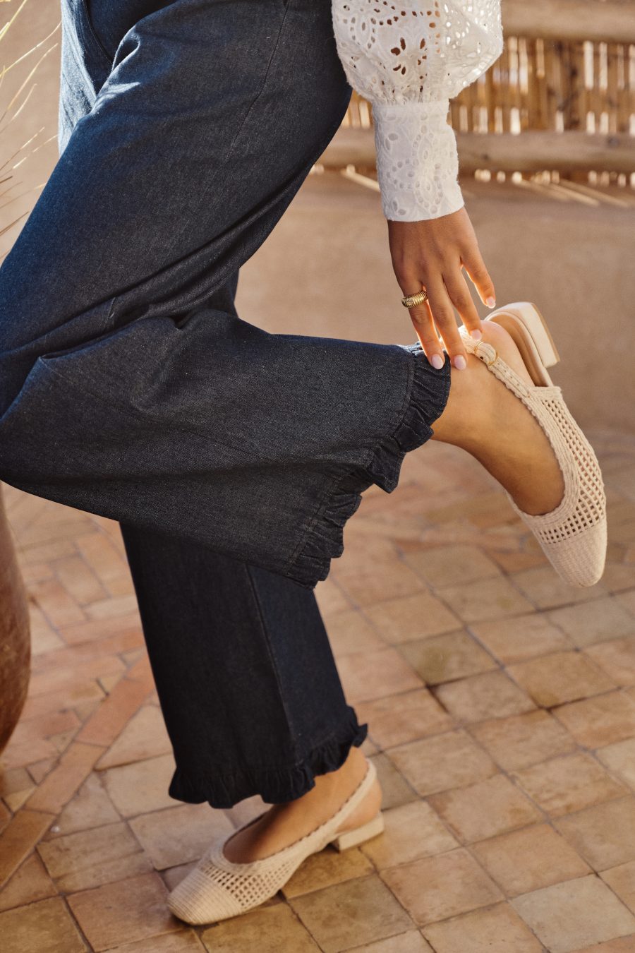 Pantalon femme Narcisse Sahoma bleu en jean finition bas à volants, porté avec une chemise blanche