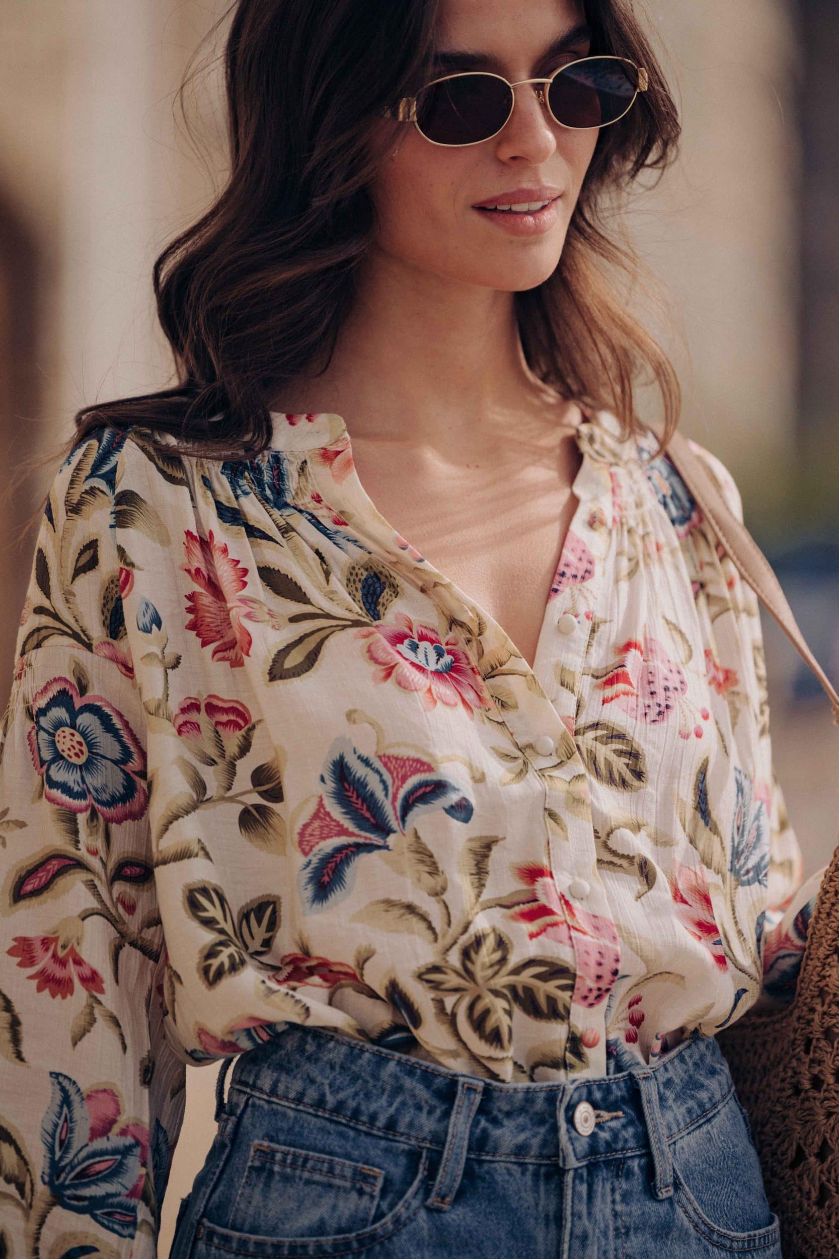 Blouse Calyne Sahoma écrue aux motifs floraux multicolore, manches longues, portée avec un jean bleu foncé