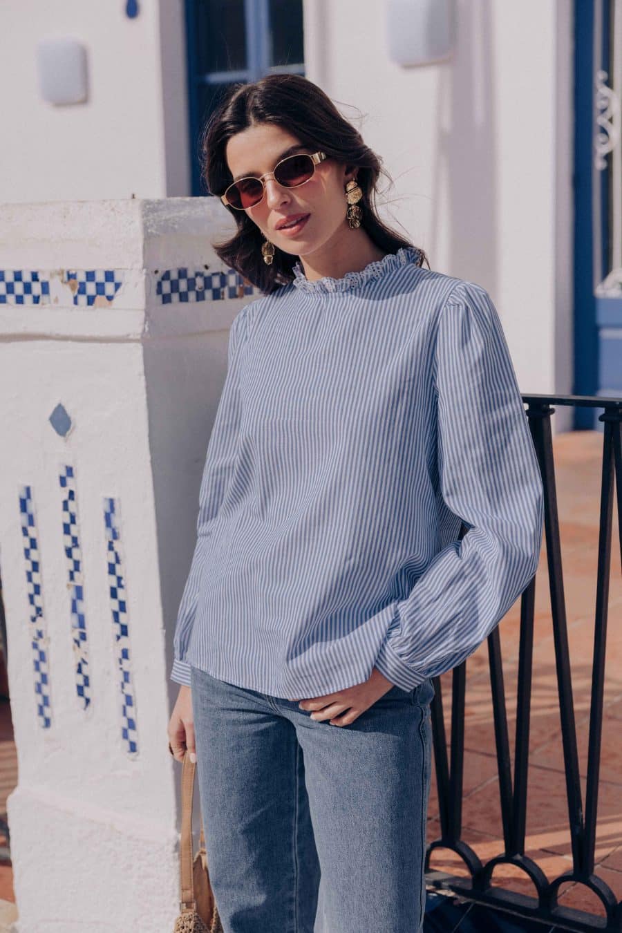 Blouse Nolane Sahoma rayée bleu et blanc, col montant à volants blanc, manches longues, portée avec un jean