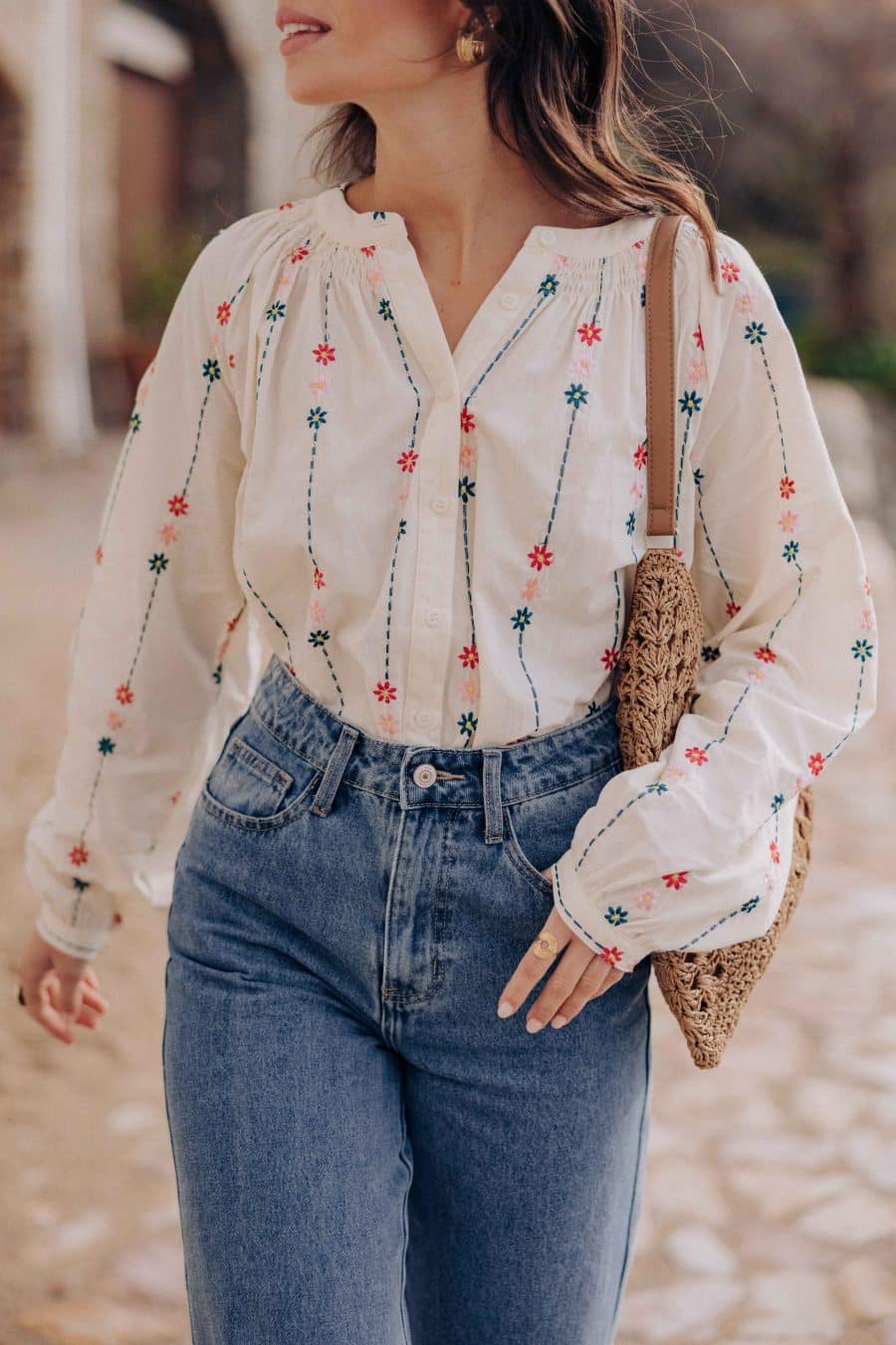 Blouse Nolwenn Sahoma écrue aux motifs floraux multicolore brodés, manches longues, portée avec un jean bleu foncé