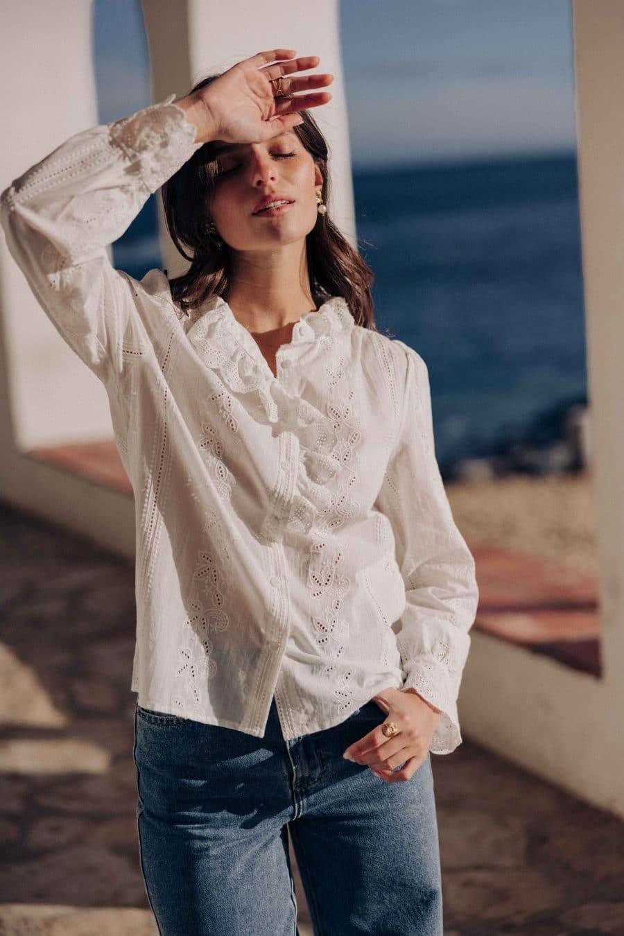 Chemise Aleia Sahoma blanche aux motifs floraux en broderie anglaise, manches longues, portée avec un jean bleu foncé