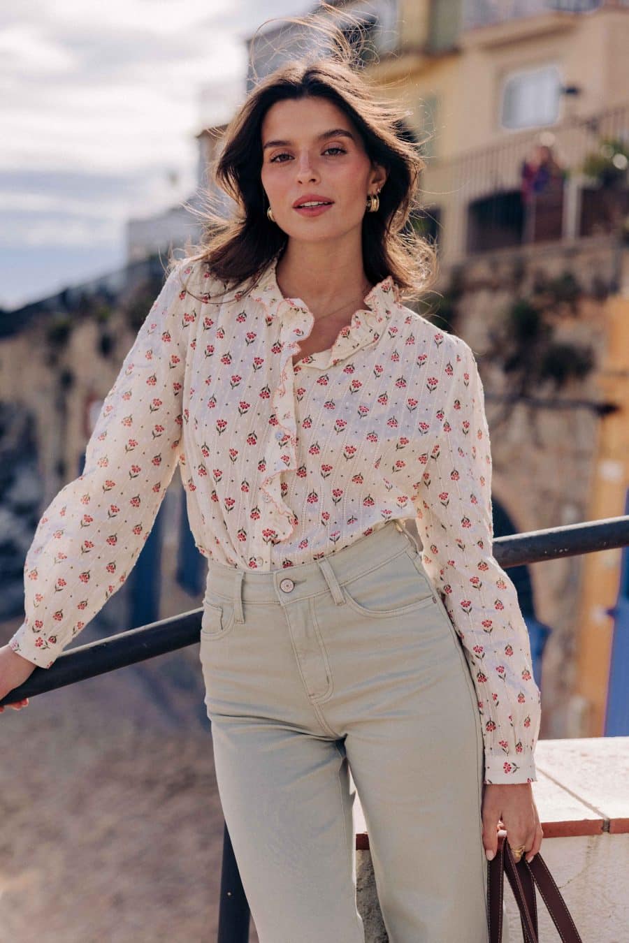 Chemise Eilis Sahoma écrue aux motifs floraux rose, col montant à volants et jabot, manches longues, portée avec un jean vert d'eau