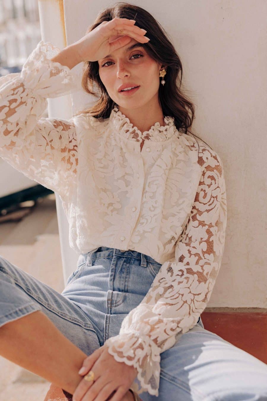 Chemise Lorna Sahoma écrue aux motifs floraux en dentelle, col montant à volants, manches longues, portée avec un jean bleu clair