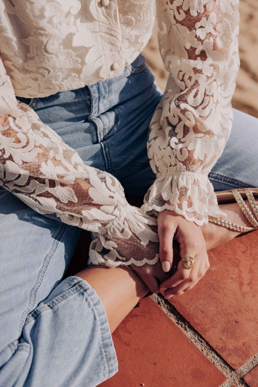 Chemise Lorna Sahoma écrue aux motifs floraux en dentelle, col montant à volants, manches longues, portée avec un jean bleu clair