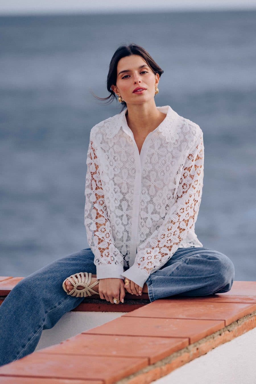 Chemise Palamos Sahoma blanche aux motifs floraux en dentelle, col revers, manches longues, portée avec un jean bleu foncé