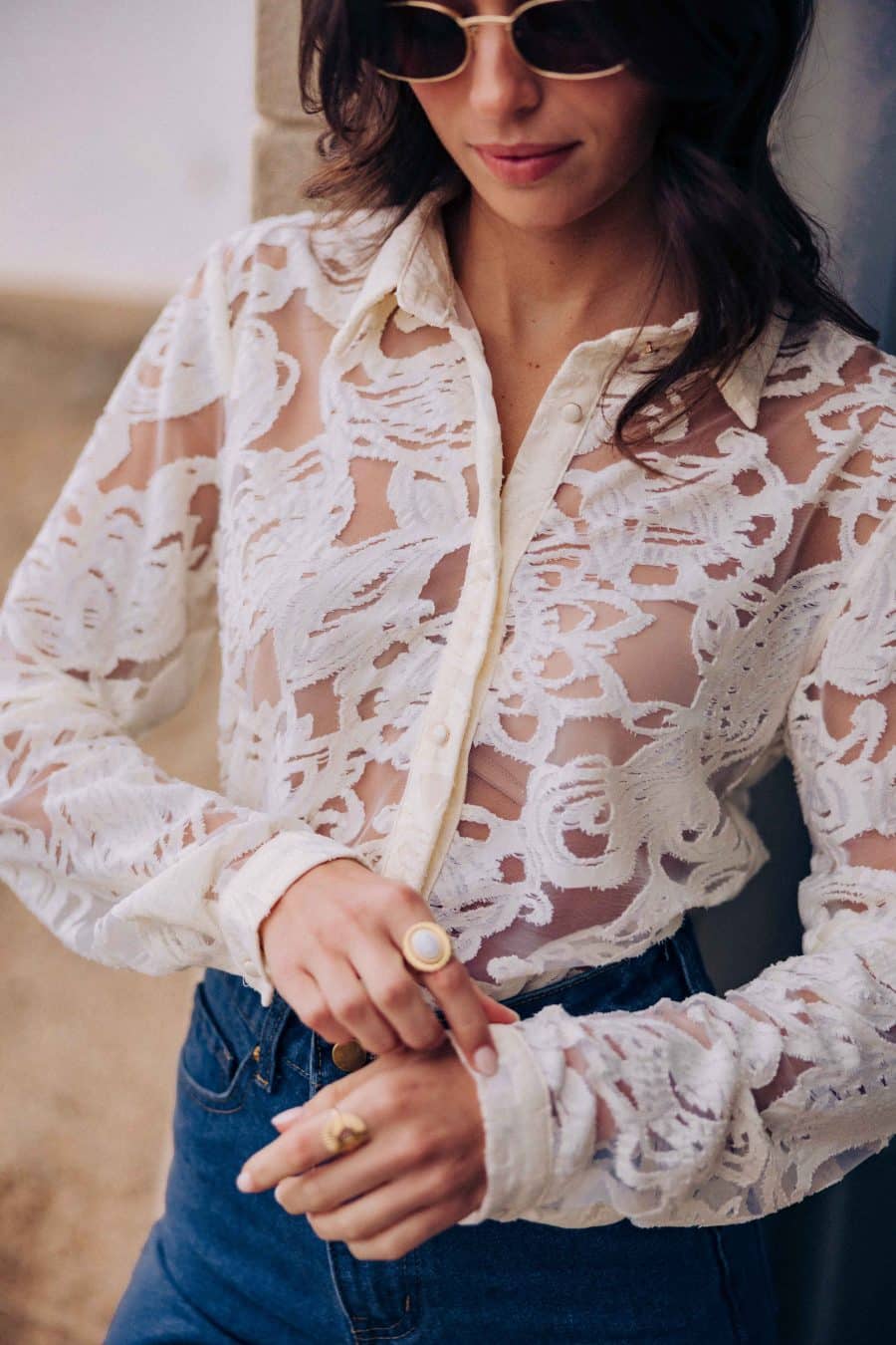 Chemise Silve semi-transparente Sahoma écrue aux motifs floraux en dentelle, col revers, manches longues, portée avec un jean bleu foncé