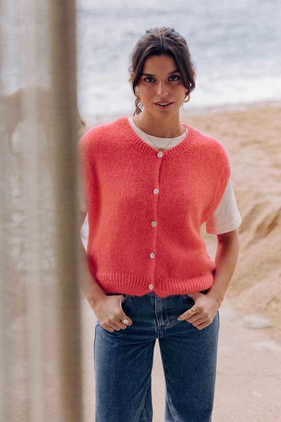 Gilet Margarida Sahoma corail uni, sans manches, portée avec un jean bleu foncé