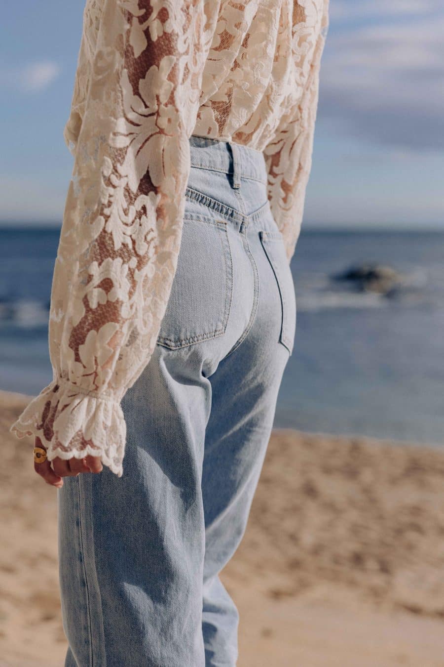 Jean Lorenzo Sahoma bleu clair, taille haute et coupe courte, porté avec une chemise en dentelle blanche
