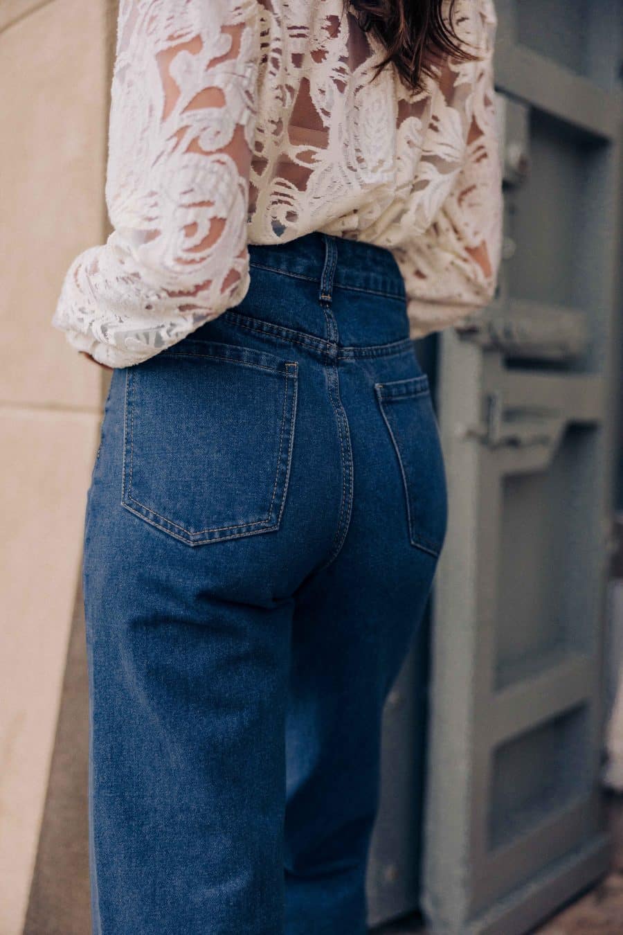 Jean Tossa Sahoma bleu brut, taille haute et coupe large, porté avec une chemise semi-transparente blanche