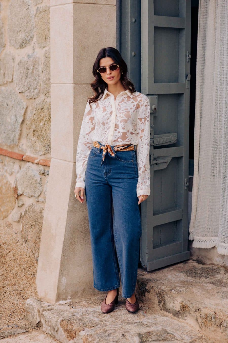 Jean Tossa Sahoma bleu brut, taille haute et coupe large, porté avec une chemise semi-transparente blanche