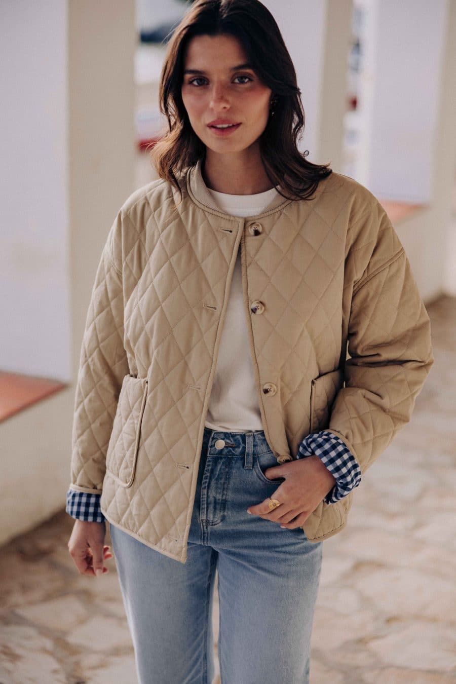 Veste matelassée Calella Sahoma beige uni, col rond, manches longues, doublure vichy bleu, portée avec un jean bleu clair