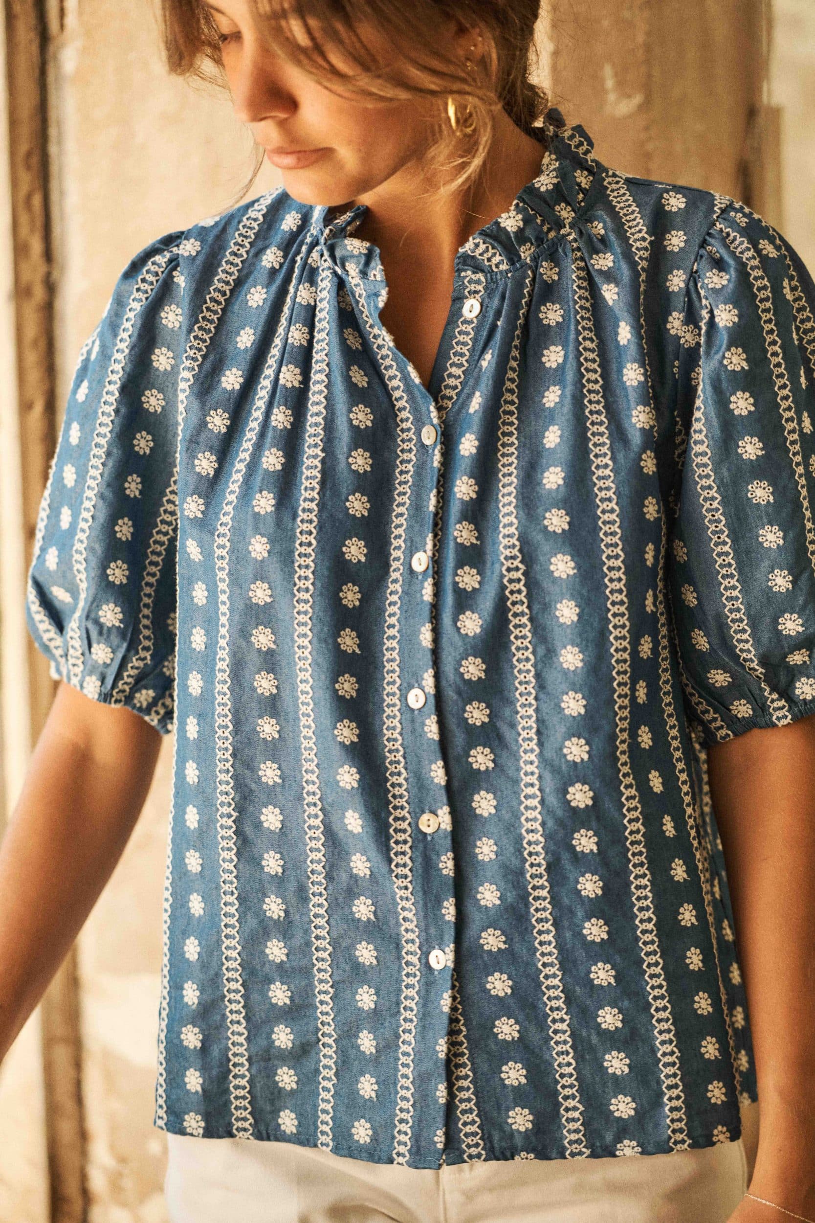 blouse-azur-bleue-sahoma-00007 Blouse femme bleu jean boutonnée à manches courtes - broderie fleurie blanche - col à volants – Élégance bohème et détails raffinés