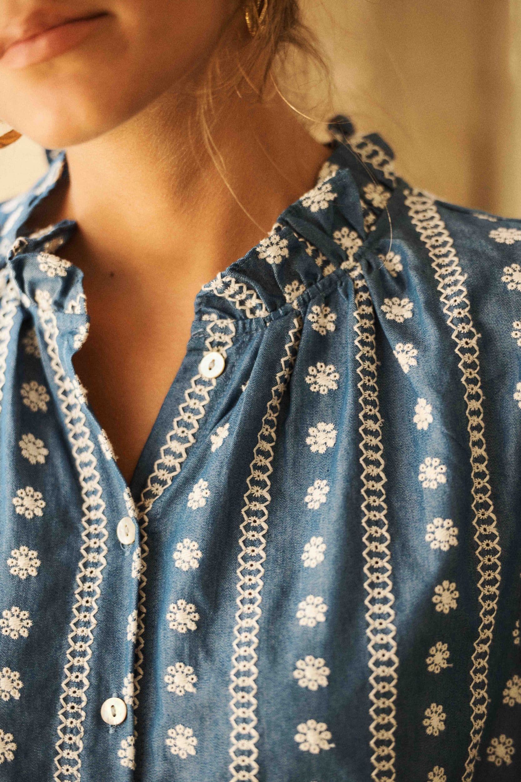 blouse-azur-bleue-sahoma-00011 Blouse femme bleu jean boutonnée à manches courtes - broderie fleurie blanche - col à volants – Élégance bohème et détails raffinés