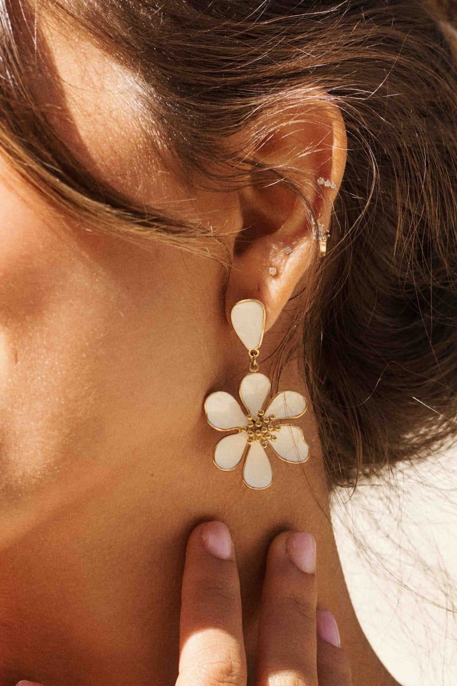 Boucles d’oreilles blanches et dorées, forme fleur en relief, posées sur fond blanc