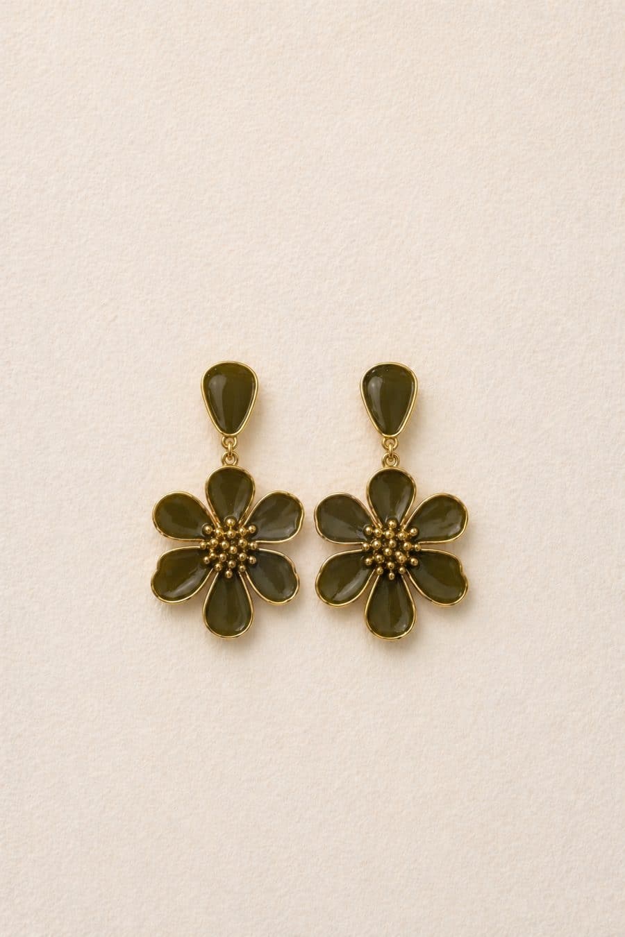 Boucles d’oreilles vertes et dorées, forme fleur en relief, posées sur fond blanc