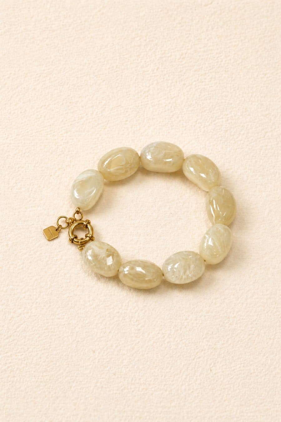 Bracelet couleur ivoire, effet marbré légèrement translucide composé de grosses perles ovales, fermoir mousqueton doré