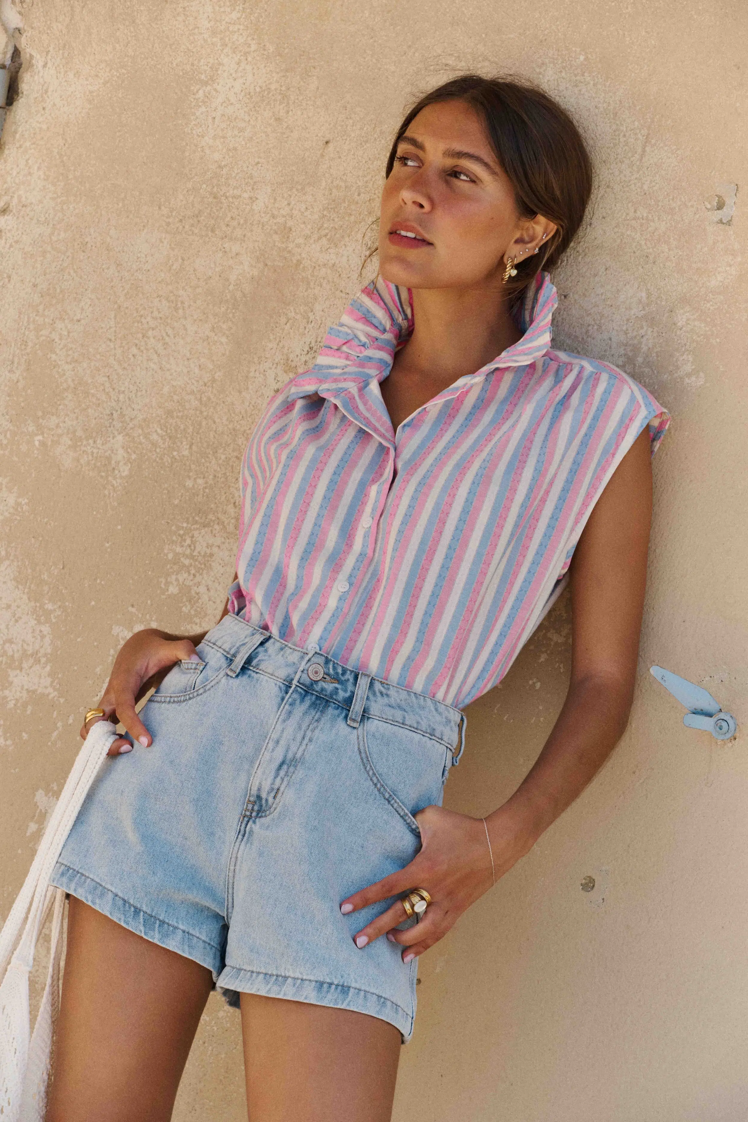 Chemise Elora Sahoma rayée bleu, blanc et rose, sans manches, portée avec un jean bleu foncé