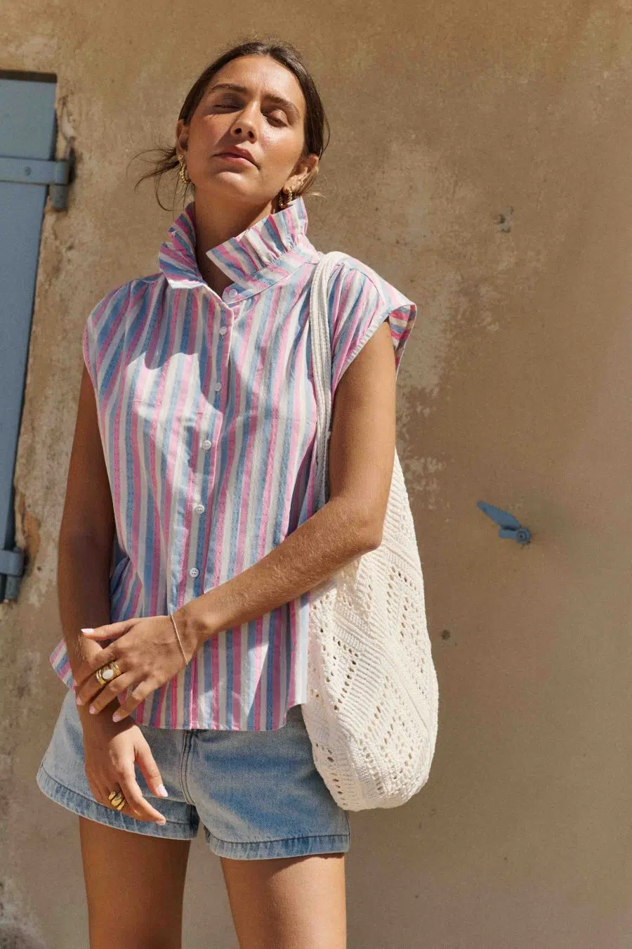 Chemise Elora Sahoma rayée bleu, blanc et rose, sans manches, portée avec un jean bleu foncé