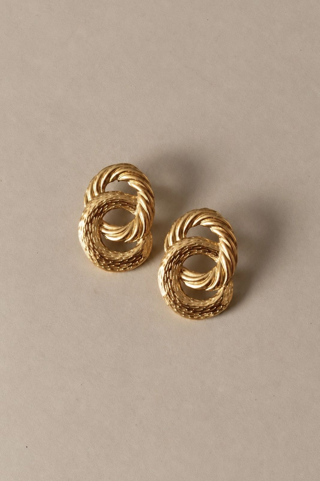 boucles-oreilles-adara-dorees-packshot-sahoma- Boucles d’oreilles dorées entrelacées effet strié | bijou sculptural aux courbes travaillées et lumineuses | Sahoma